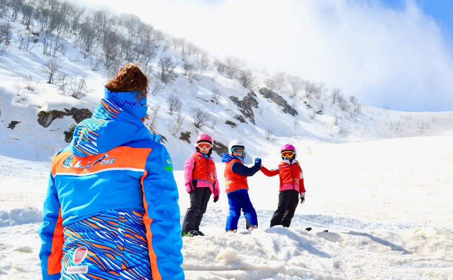 Maestro di sci con bambini felici a Limone durante una delle lezioni di sci per bambini (da 6 anni) per principianti