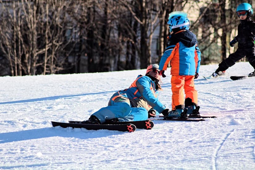 Maestro di sci che segue da vicino un bambino a Limone durante una delle lezioni private di sci per bambini di tutti i livelli.