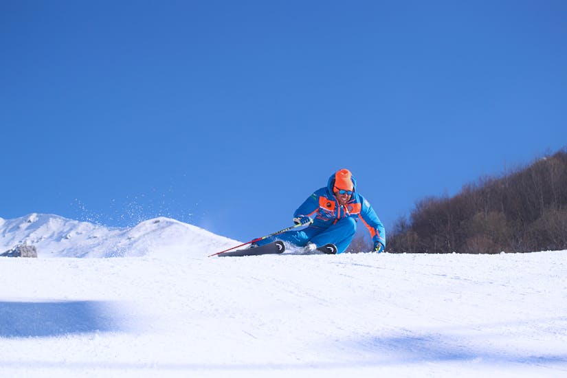 Maestro di sci che corre a tutta velocità sulla neve di Limone prima di una delle lezioni private di sci per adulti per tutti i livelli.