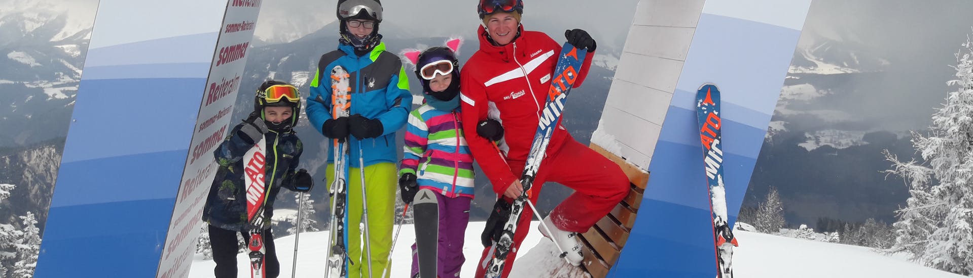 A group of skiers with their ski instructor from the Reiteralm Ski School during their kids ski lessons for all levels in Schladming.
