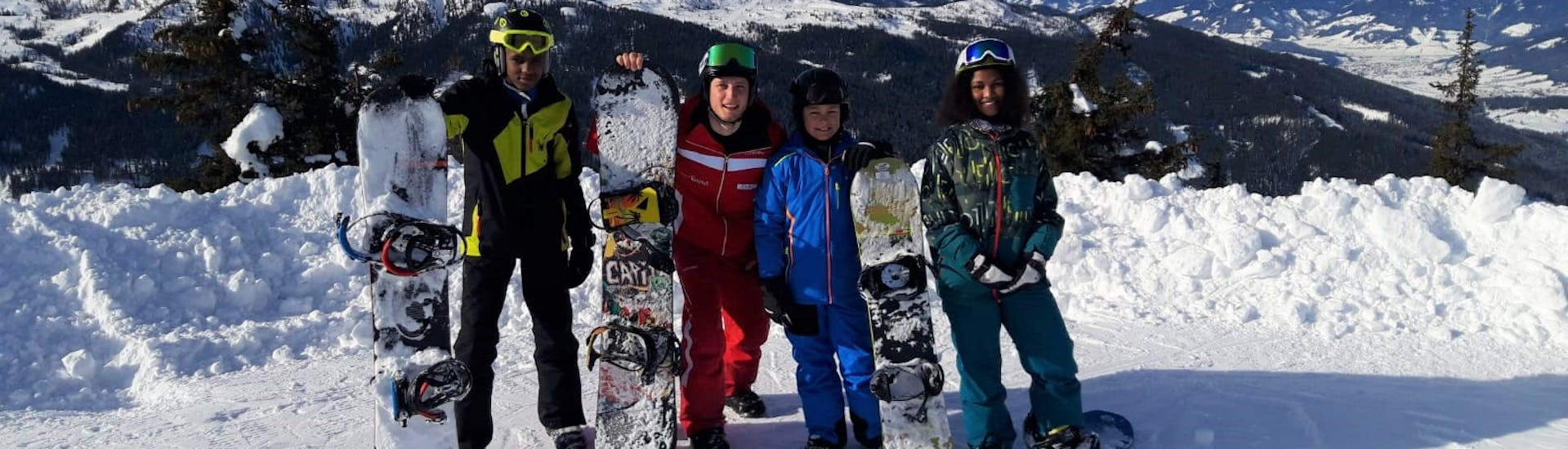 Eine Gruppe Snowboarder mit ihrem Snowboardlehrer von der Skischule Reiteralm während ihrem Snowboardkurs für Kinder und Erwachsene in Schladming. 