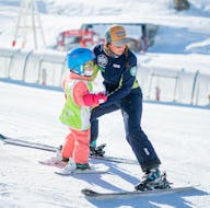 Un moniteur aide un enfant à trouver son équilibre pendant un Cours particulier de ski pour Enfants avec Prosneige Tignes.