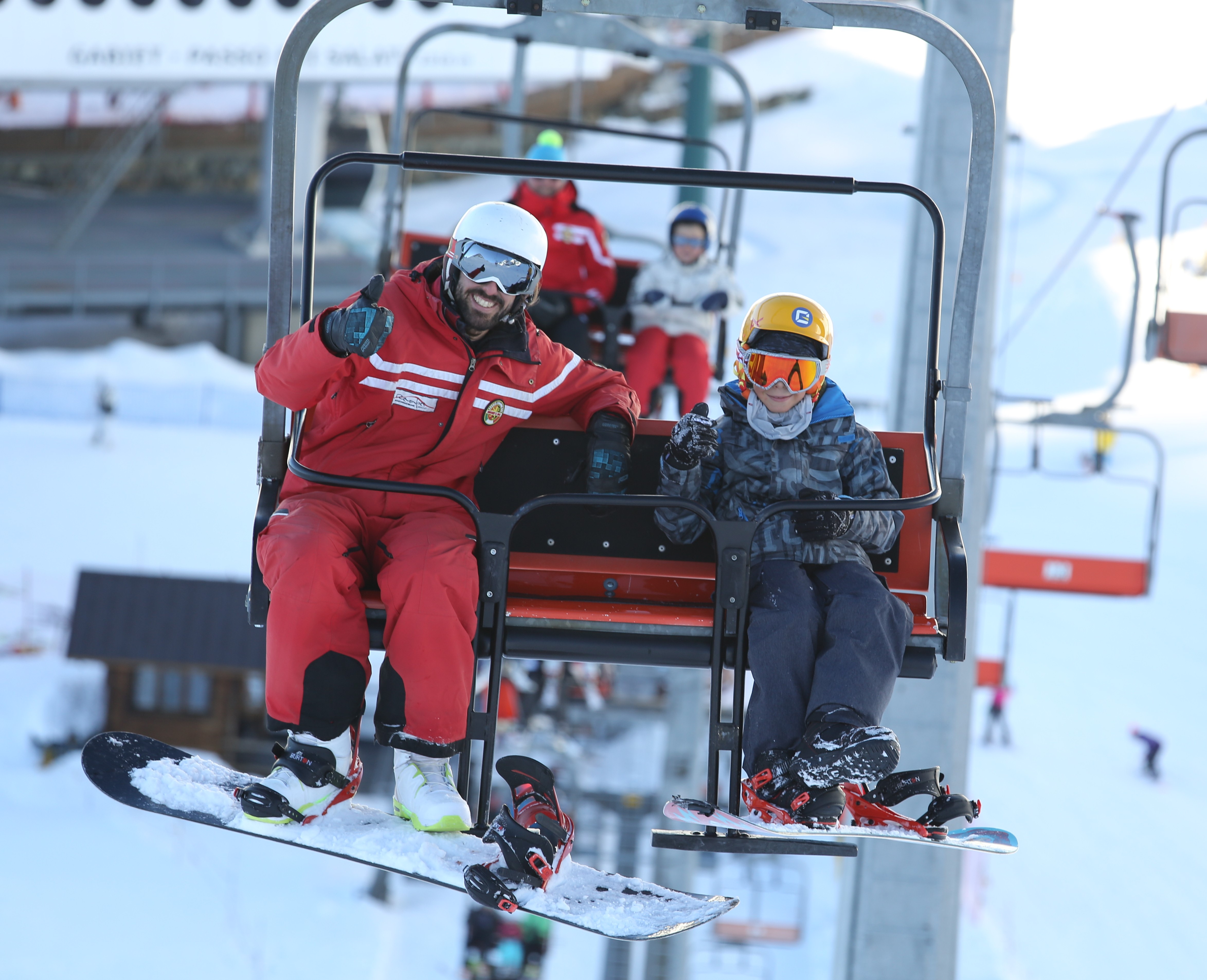 Snowboard instructor and kid on a chairlift during one of the private snowboarding lessons for kids and adults of all levels.