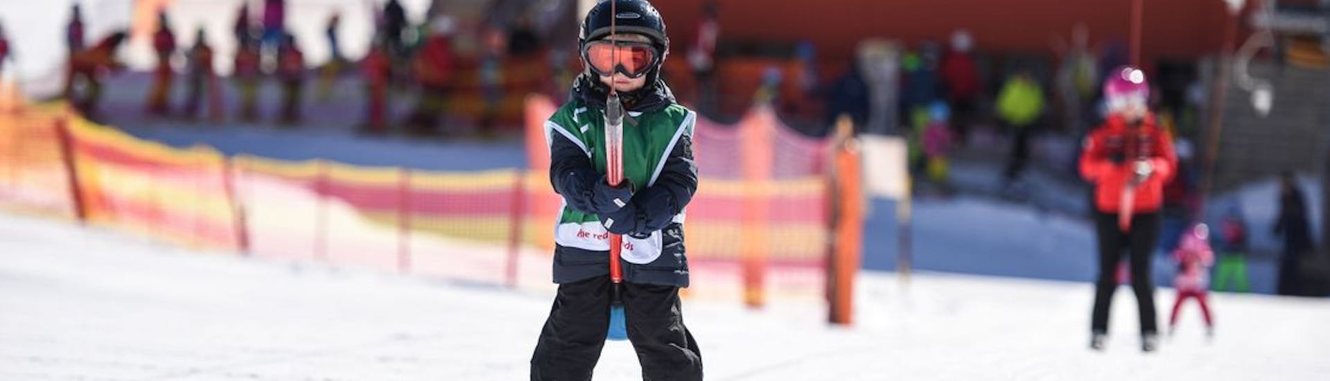 Ein kleiner Junge lernt im privaten Kinder-Skikurs der Schweizer Skischule St. Moritz the Red Legends, wie man einen Skilift bedient.