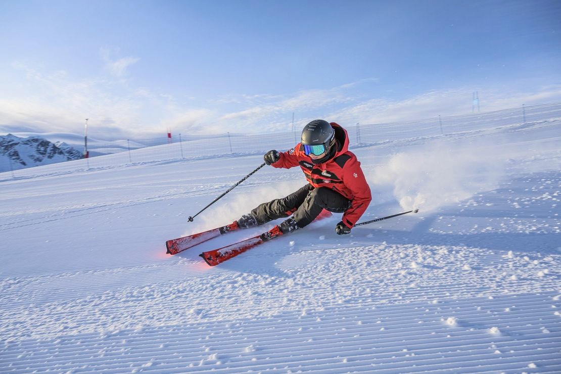A skier is racing down the slopes during private ski lessons for adults of all levels with Swiss Ski School St. Moritz the Red Legends.