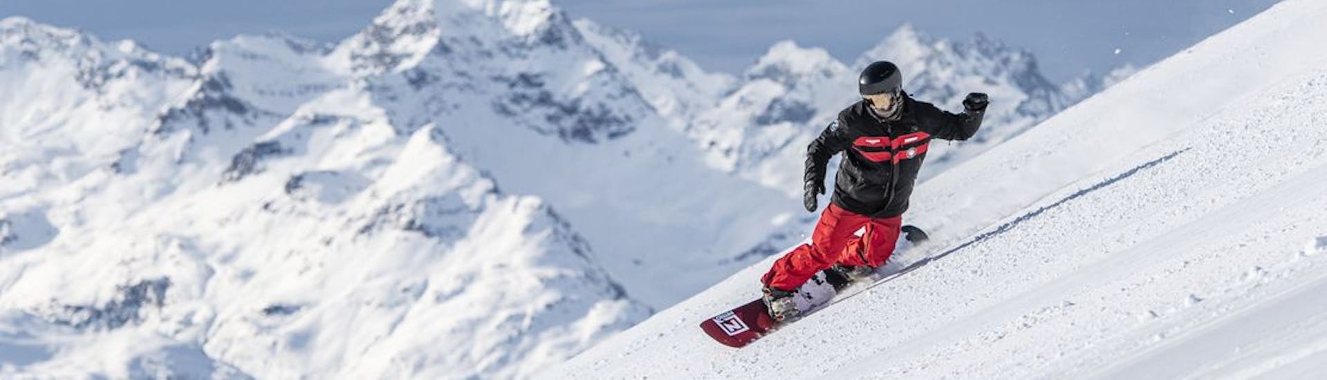 A snowboarder is going down the slopes of St. Moritz during private snowboarding for kids and adults of all levels with Swiss Ski School St. Moritz The Red Legends.