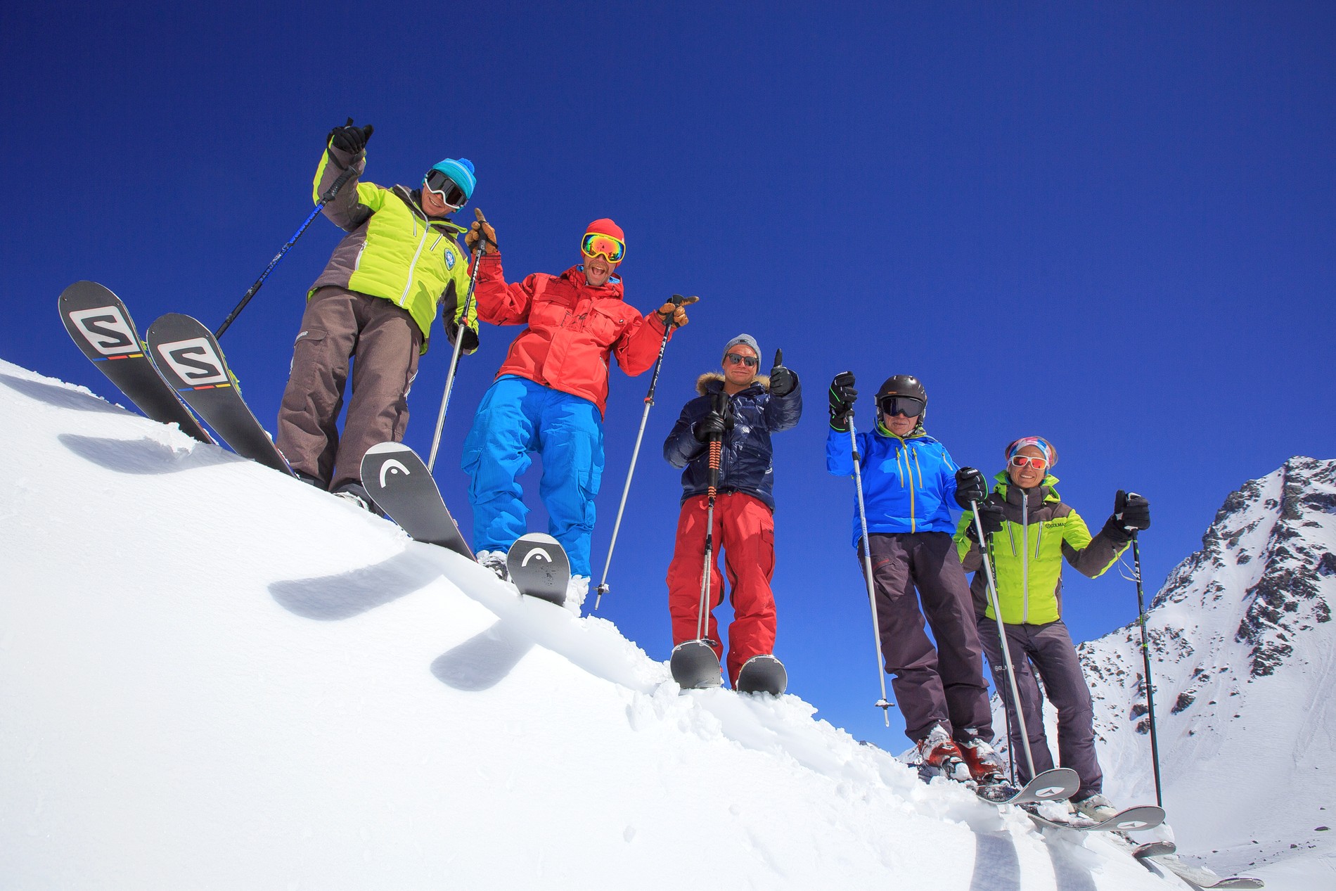 Skiers are standing on a snowy ridge during their Adult Ski Lessons (from 14 y.) - Max 8 per group with Prosneige Alpe d'Huez.