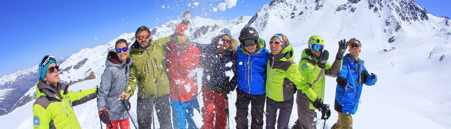 Des skieurs jettent de la neige en l'air après leur Cours de ski Adultes (dès 14 ans) - Max 8 par groupe avec Prosneige Alpe d'Huez.