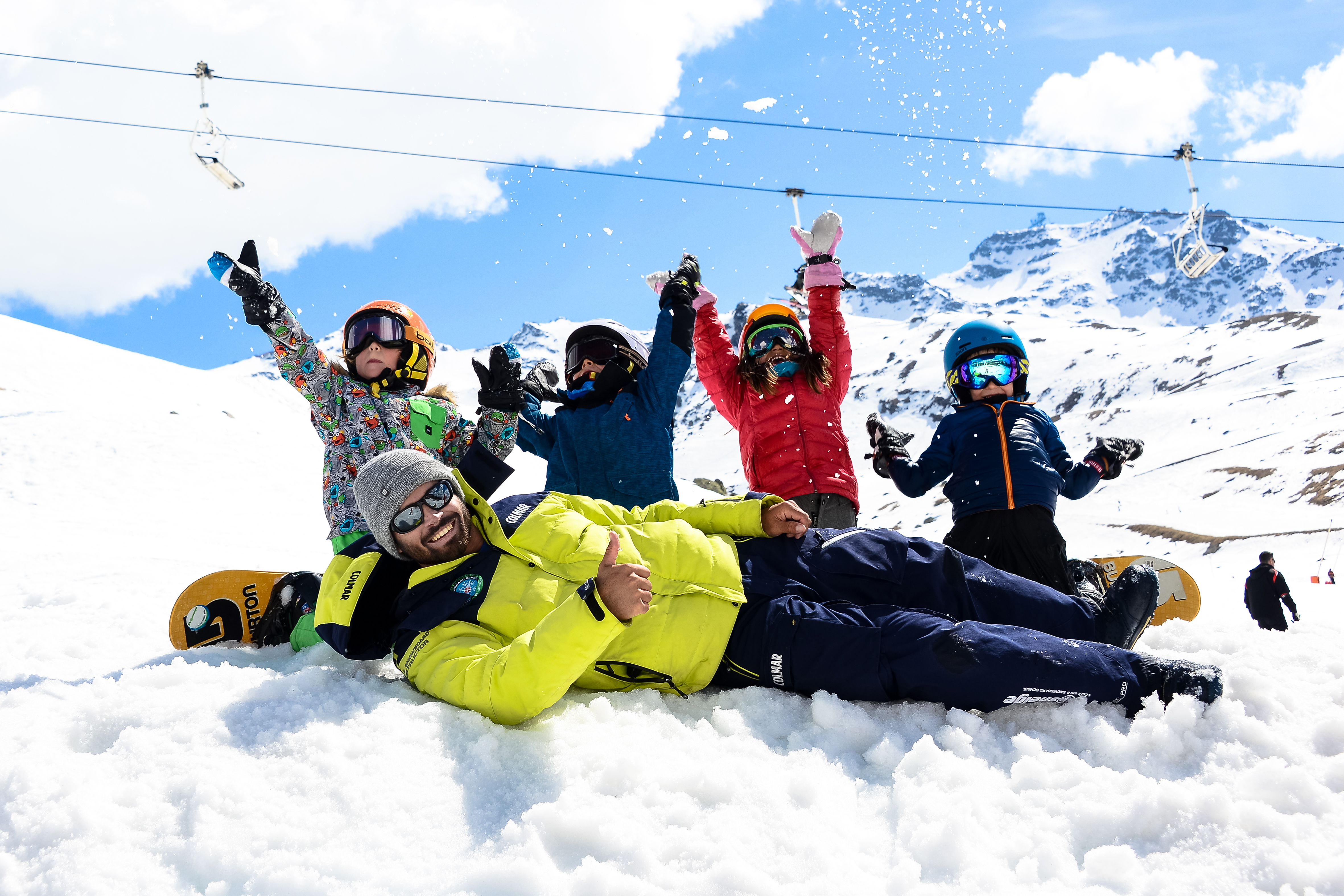 Children having fun with their instructor during snowboarding lessons for kids with Prosneige Alpe d'Huez.