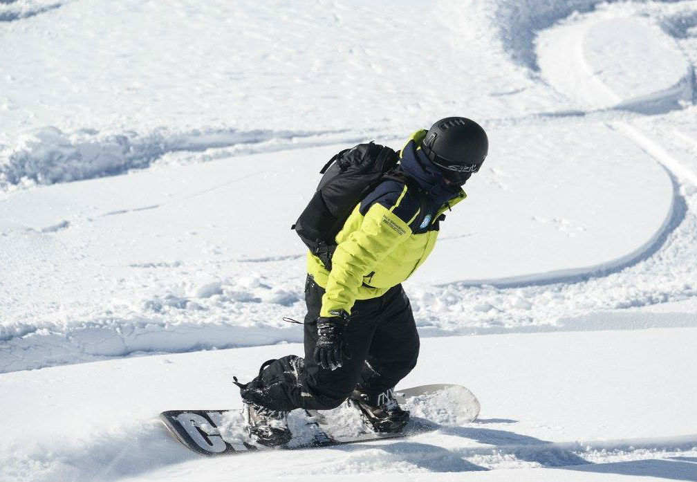 A snowboarder crosses the powder during snowboarding lessons for adults with Prosneige Alpe d'Huez.