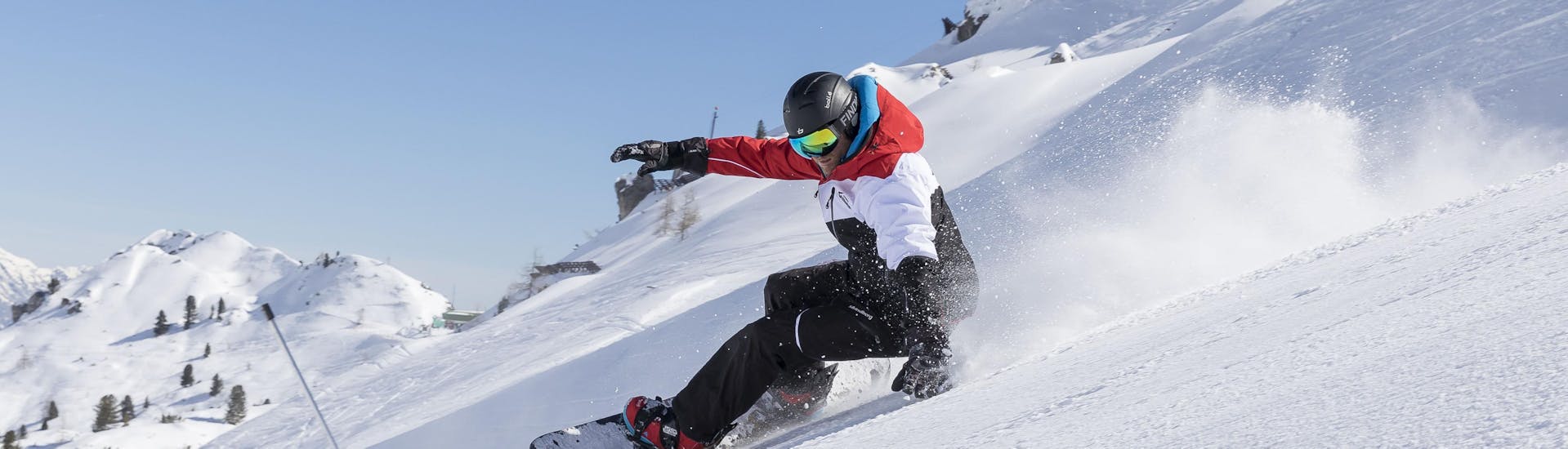 A snowboarder is shredding down a slope during his snowboarding lessons for advanced boarders in Stubai.