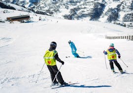 Budding skiers skiing down a slope with their ESI Ski Family instructor during a kids ski lesson for 5 to 13 year olds in Les Ménuires. 
