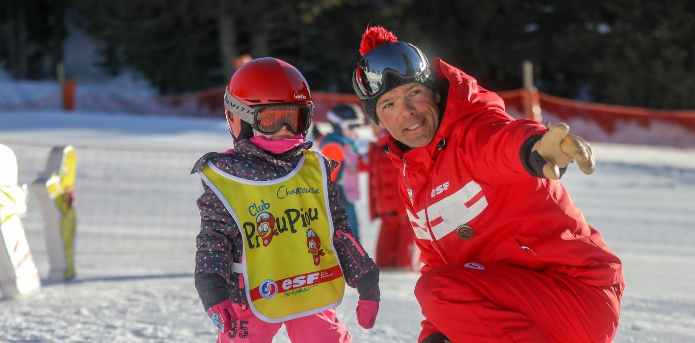 An instructor of the Ski School ESF Valmorel accompanies a young skier during his first steps in kids ski lessons at the Piou-Piou club.