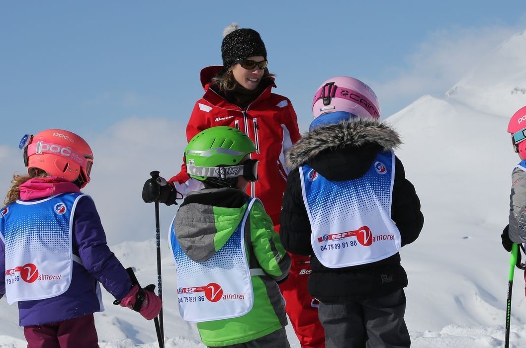 An instructor of the Ski School ESF Valmorel supervises young skiers during kids ski lessons.