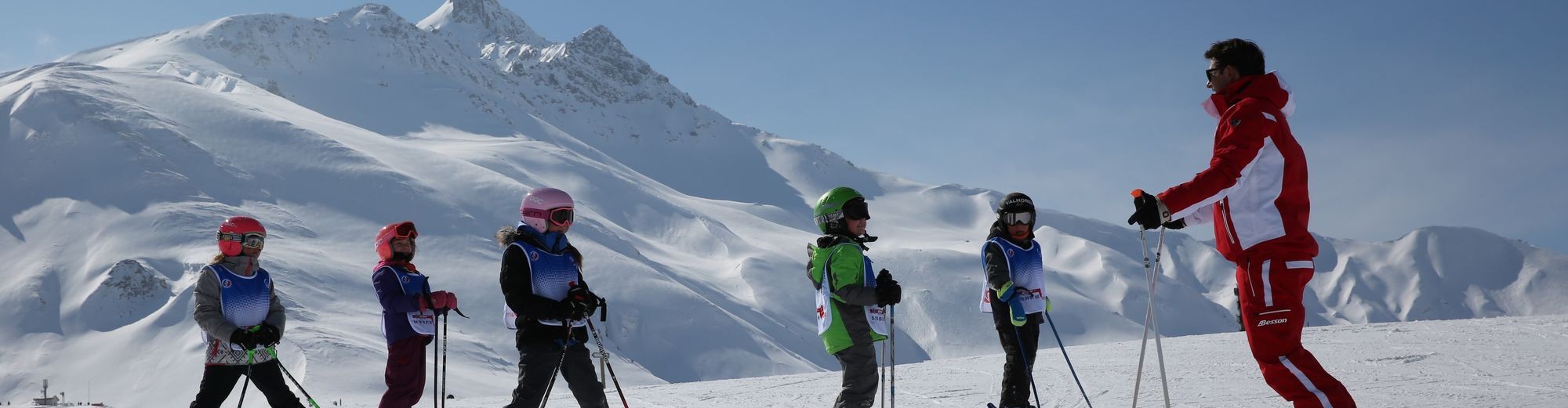 An instructor of the Ski School ESF Valmorel explains the different skiing techniques to his pupils during kids ski lessons from 5 to 12 years old.