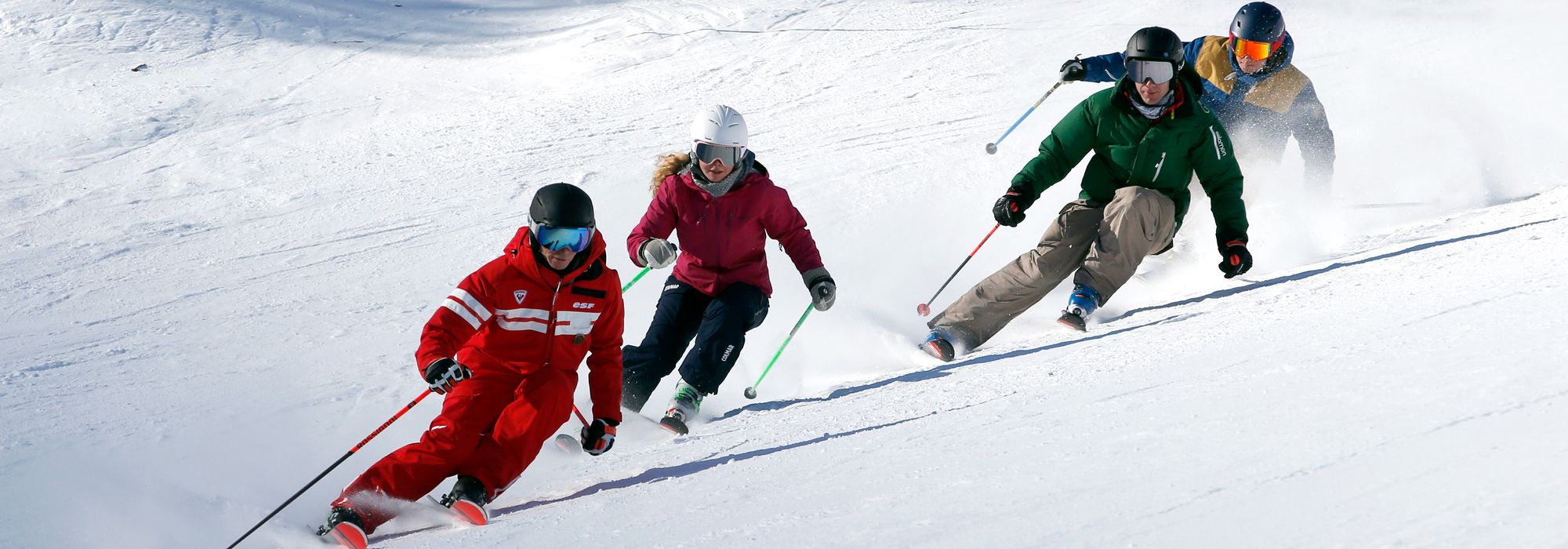 Skiers carving down the slopes with their Ski School ESF Valmorel instructor during teens and adults ski lessons.