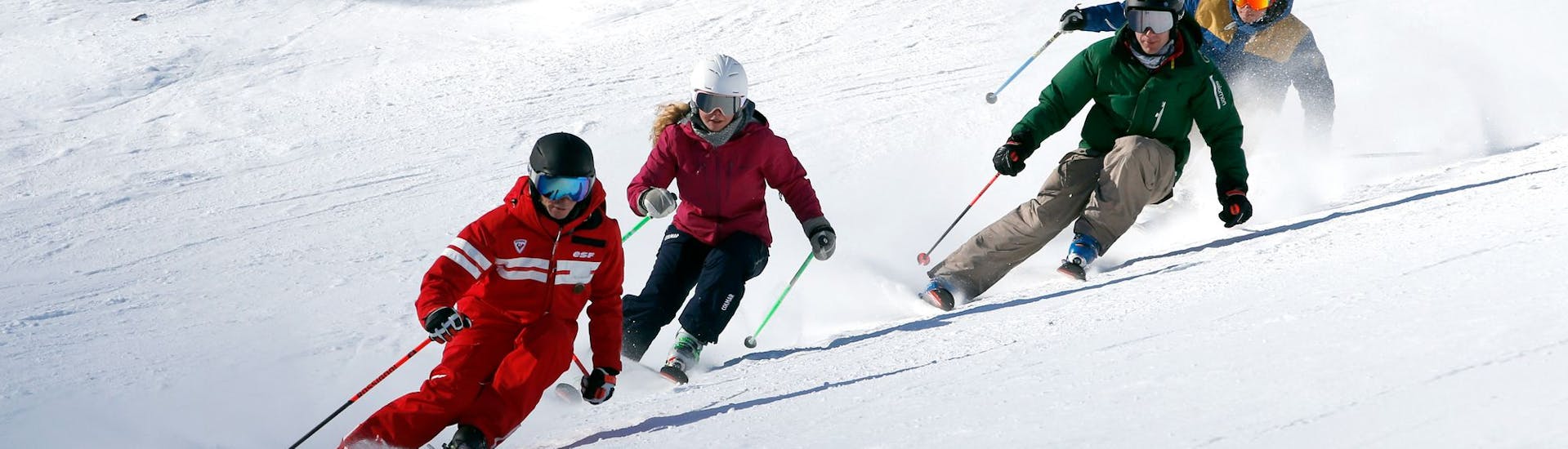 Skiers carving down the slopes with their Ski School ESF Valmorel instructor during teens and adults ski lessons. 