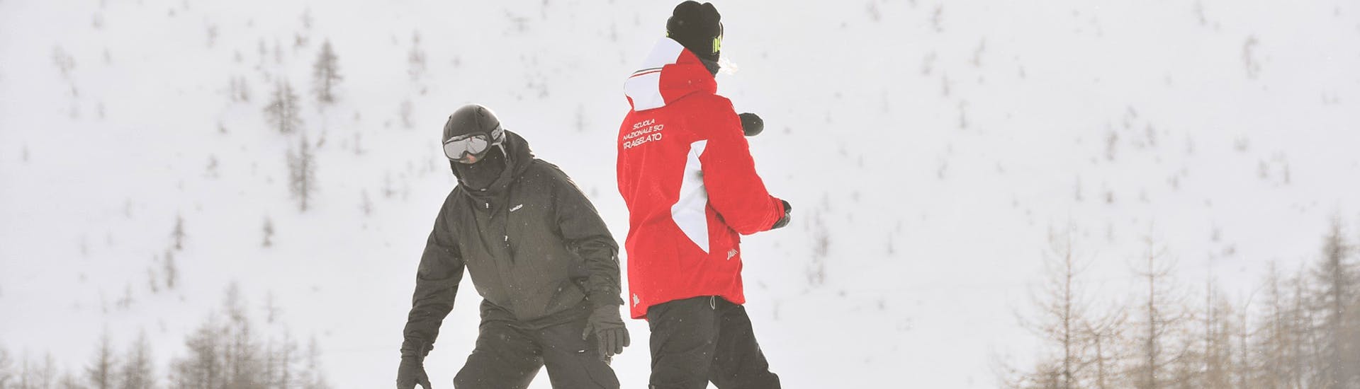 Moniteur de snowboard donnant des conseils à un participant à Pragelato lors d'une des cours particuliers de snowboard pour adultes de tous niveaux.