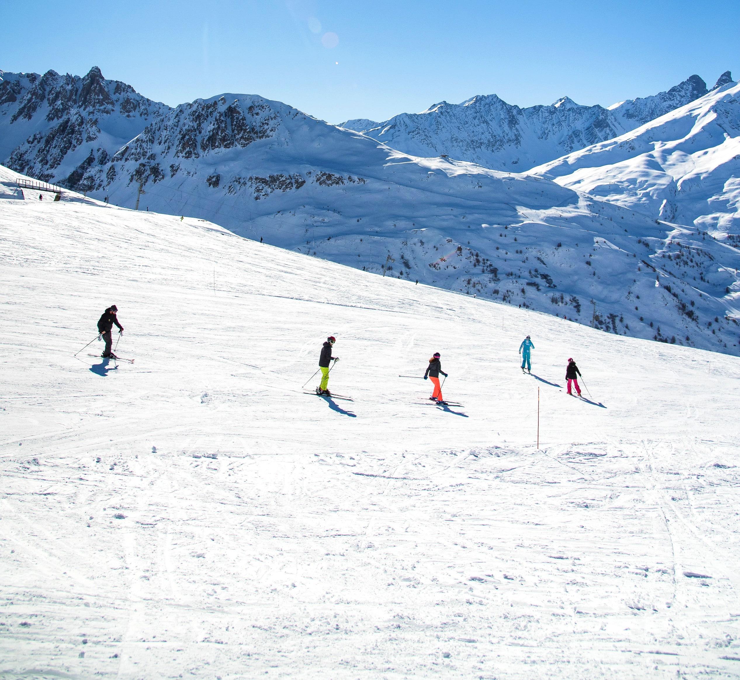 Skiers are skiing down a slope in confidence during their Adult Ski Lessons for All Levels with the ski school ESI Ski Family in Risoul.