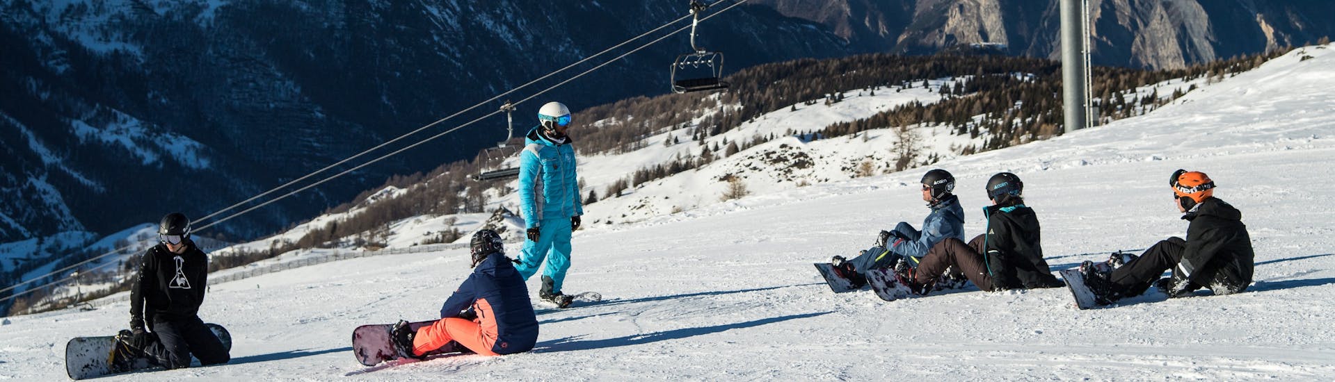 Des snowboardeurs prenant des cours de snowboard avec ESI Ski Family à Risoul écoutent leur moniteur.