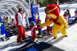 A child meets Piou Piou during the "Baby Skieur" kids ski lessons for kids of 2 to 3 years old at the ESF of Serre Chevalier - Villeneuve.