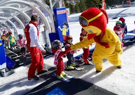 A child meets Piou Piou during the "Baby Skieur" kids ski lessons for kids of 2 to 3 years old at the ESF of Serre Chevalier - Villeneuve. 