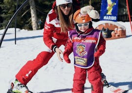 A young skier takes his first steps during the "Club Piou Piou" kids ski lessons with an instructor from the ESF Serre Chevalier - Villeneuve.