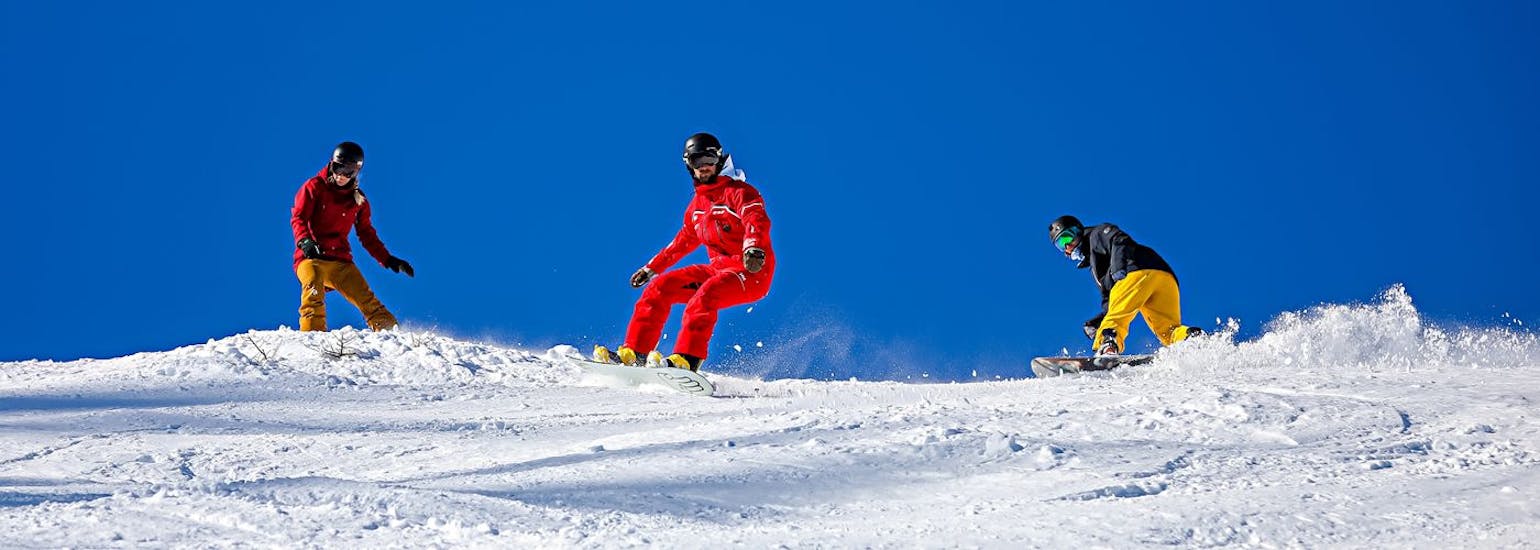 Un maestro di snowboard fa le curve sulle piste durante le lezioni di snowboard a partire da 9 anni con la Scuola di Sci ESF Serre Chevalier - Villeneuve.