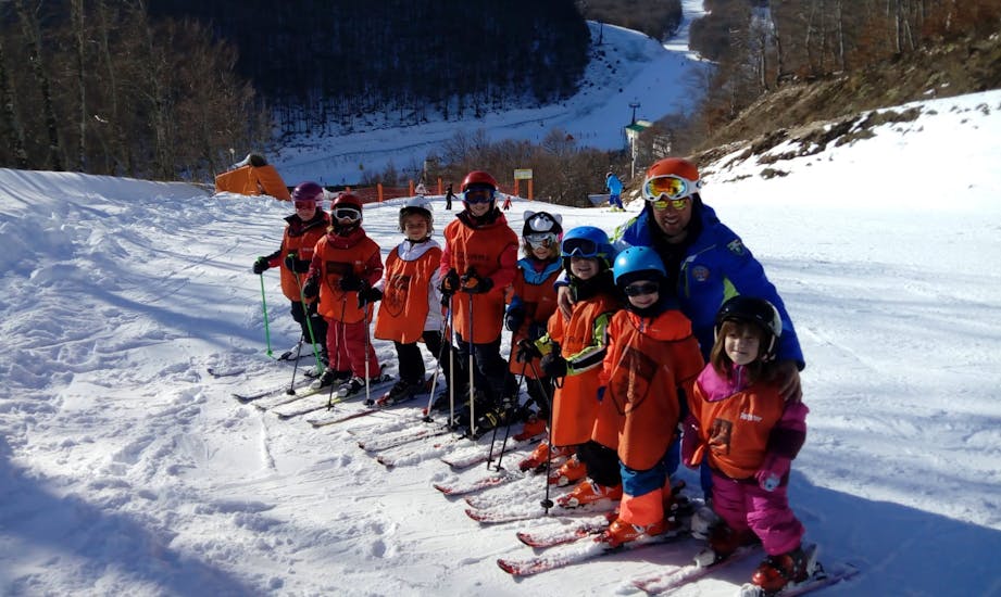Bambini e maestro di sci che si divertono durante una delle lezioni di sci per bambini di tutti i livelli a Roccaraso.