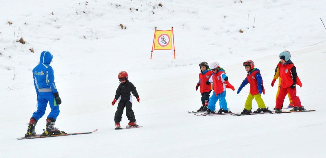 Bambini che si divertono con il maestro di sci a Roccaraso durante una delle lezioni private di sci per bambini a tutti i livelli.