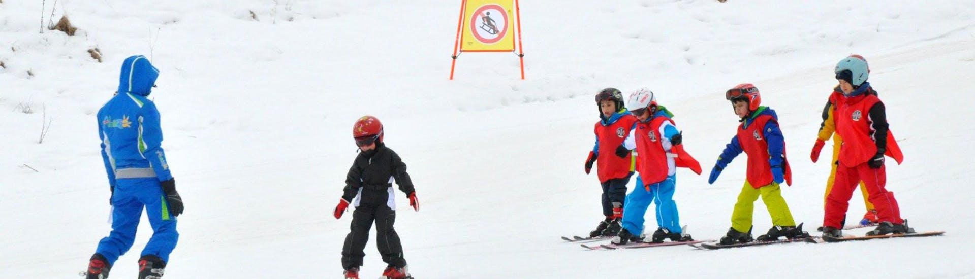 Bambini che si divertono con il maestro di sci a Roccaraso durante una delle lezioni private di sci per bambini a tutti i livelli.
