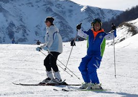 Participant and ski instructor trying the first blue slope during one of the private adults ski lessons for all levels. 