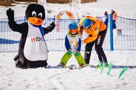 Ein Lehrer bringt einem Kind während des Kinder-Skikurses das Schneepflügen bei - Halbtag mit HSKI Zakopane.
