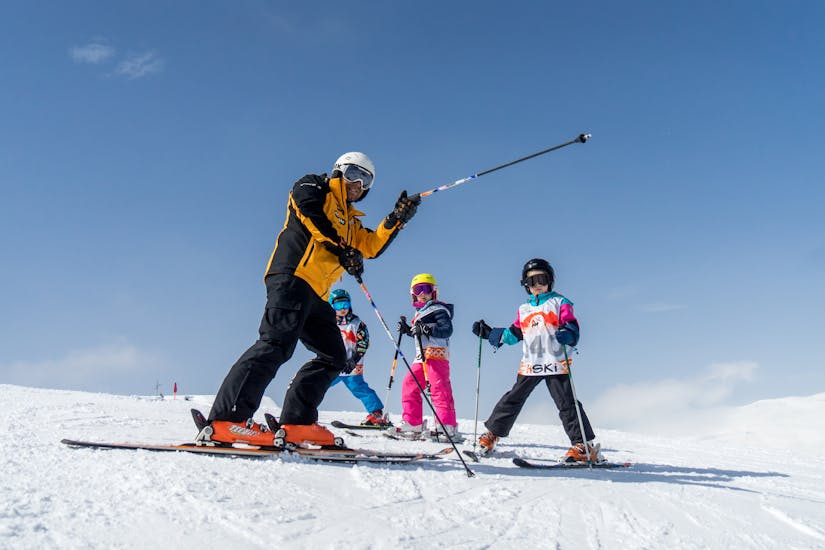 A ski instructor showing three kids the way on the slope during Private Skiing Lessons for Kids of All Levels with HSKi Zakopane.