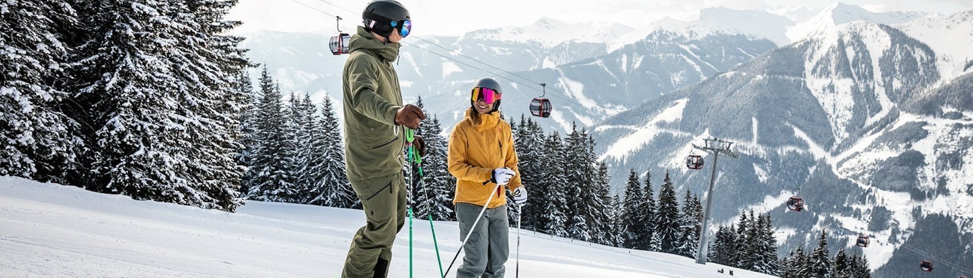 Two skiers enjoy the view of the Saalbach-Hinterglemm ski area during their private ski lessons for families with the OnSki ski school.