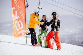 Twee skiërs met hun skileraar op de top van de piste tijdens privé-skilessen voor volwassenen van alle niveaus met HSKI Zakopane. 