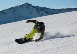 Een snowboarder gaat naar beneden tijdens een snowboardles voor volwassenen voor alle niveaus in Astún met skischool FreeXDay.