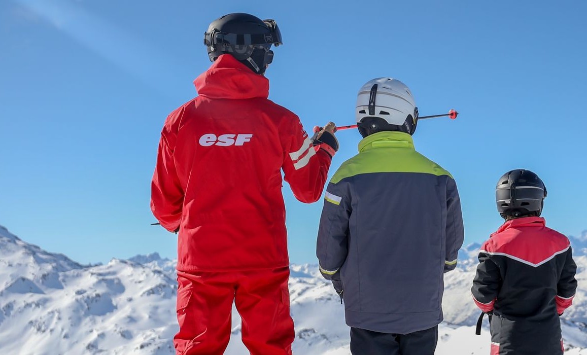 Two students and their instructor from the ski school ESF Abriès Haut-Guil contemplate the slopes during private ski lesson for kids. 