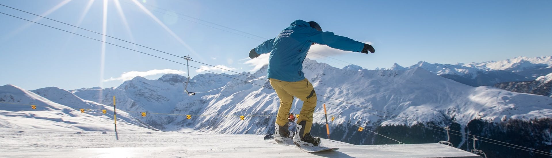 A snowboarder is doing tricks during private snowboarding lessons for kids and adults for advanced snowboarders with Swiss Ski School Davos.