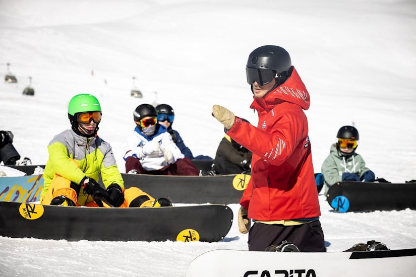 Durante le lezioni private di snowboard per gruppi - tutti i livelli con Vacancia, l'istruttore spiega al gruppo l'esercizio successivo.
