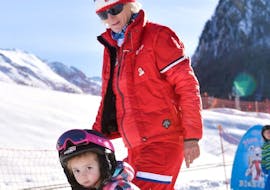 A child learns the basics of skiing with his ESF Ceillac instructor during kids ski lessons for beginners. 