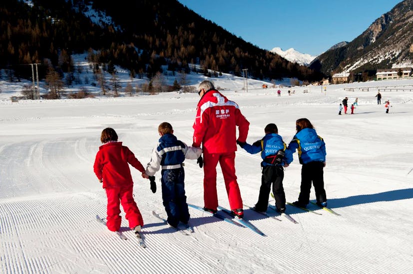 Un moniteur de l'ESF Ceillac guide des enfants pour leurs premiers pas en ski pendant un cours de ski enfants pour débutants. 