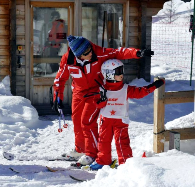 An instructor from the ski school ESF Ceillac helps a student to take the ski lift during kids ski lessons for all levels.