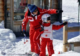 An instructor from the ski school ESF Ceillac helps a student to take the ski lift during kids ski lessons for all levels. 
