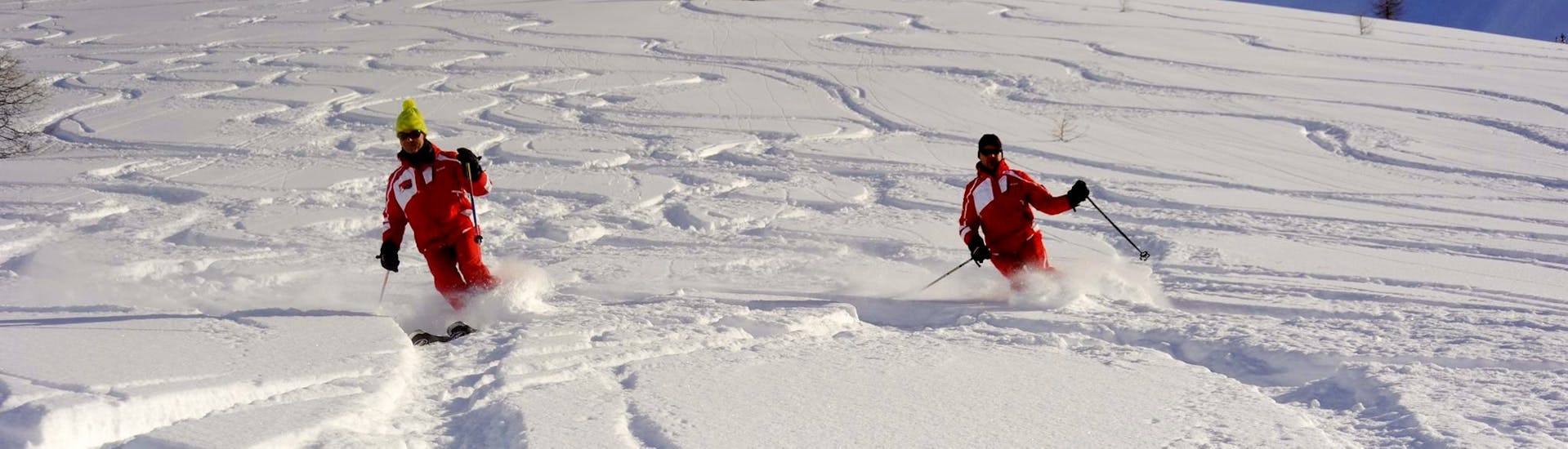 Deux skieurs traversent un champ de poudreuse pendant un cours de ski pour ados et adultes avec l'ESF Ceillac.