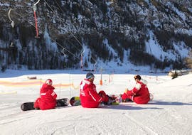 Des moniteurs de l'ESF Ceillac font une pause sur les pistes pendant un cours de snowboard pour débutants. 