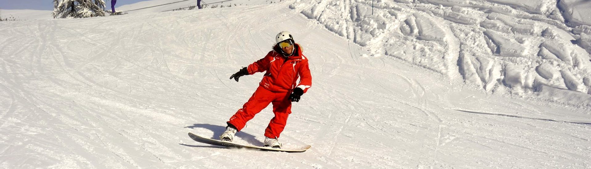 An instructor from the ski school ESF Ceillac shows how to make turns during a snowboarding lesson for beginners. 