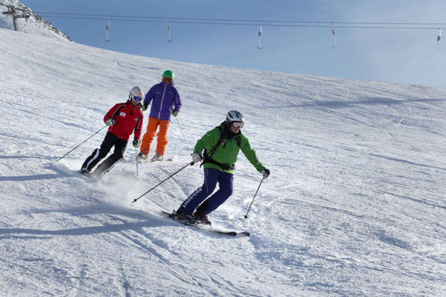 Deux participants aux cours de ski particuliers pour adultes de tous niveaux à Sölden suivent les instructions de leur moniteur privé d'Alpinsport Obergurgl sur les pistes.