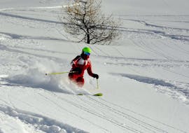 An instructor of the ski school ESF Ceillac skiing through a field of powder snow during private ski lessons for adults.