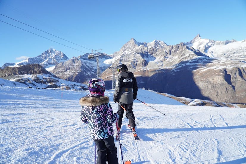 Twee kleine skiërs volgen hun instructeur van de PDS Snowsports skischool tijdens een kinderskiles.
